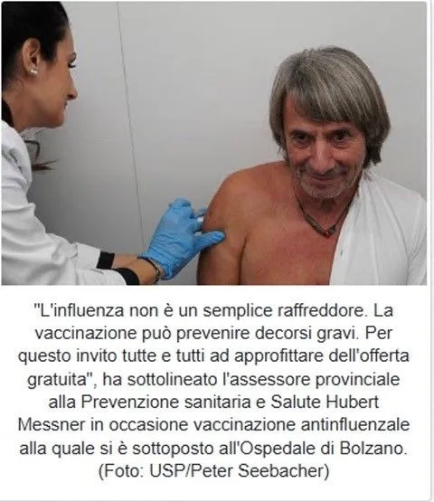 Un uomo riceve un’iniezione al braccio da un’operatrice sanitaria con guanti blu, in un ambulatorio medico.