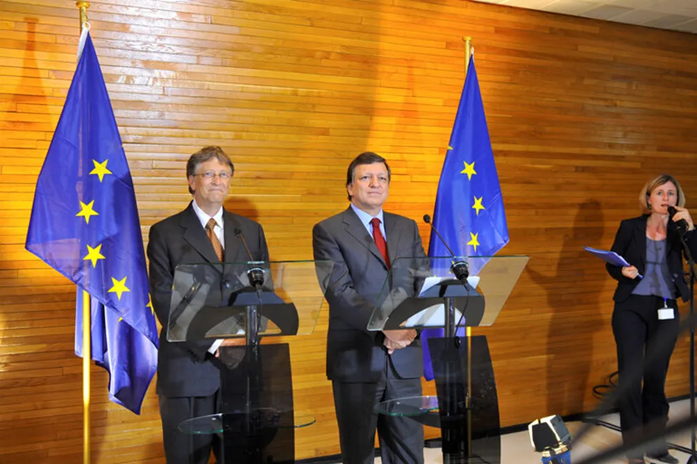 tre persone in abito formale durante un evento istituzionale con bandiere dell Unione Europea sullo sfondo